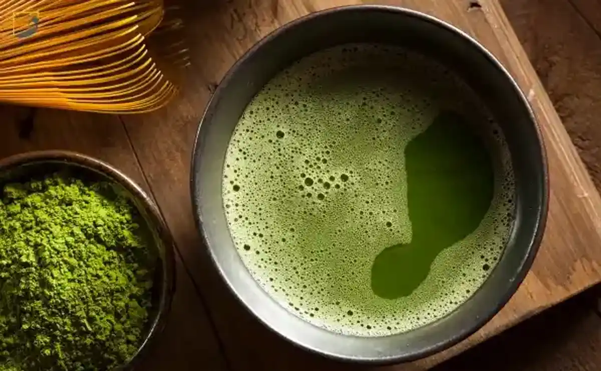 چای ماچا خوشرنگ روی تخته چوبی در کنار ظرف پودر ماچا